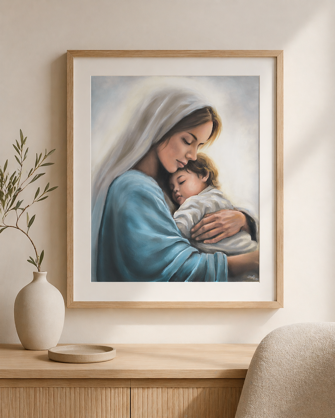 Framed artwork of Mother Mary holding little child Jesus. Canvas is on a wall above a wooden console table.
