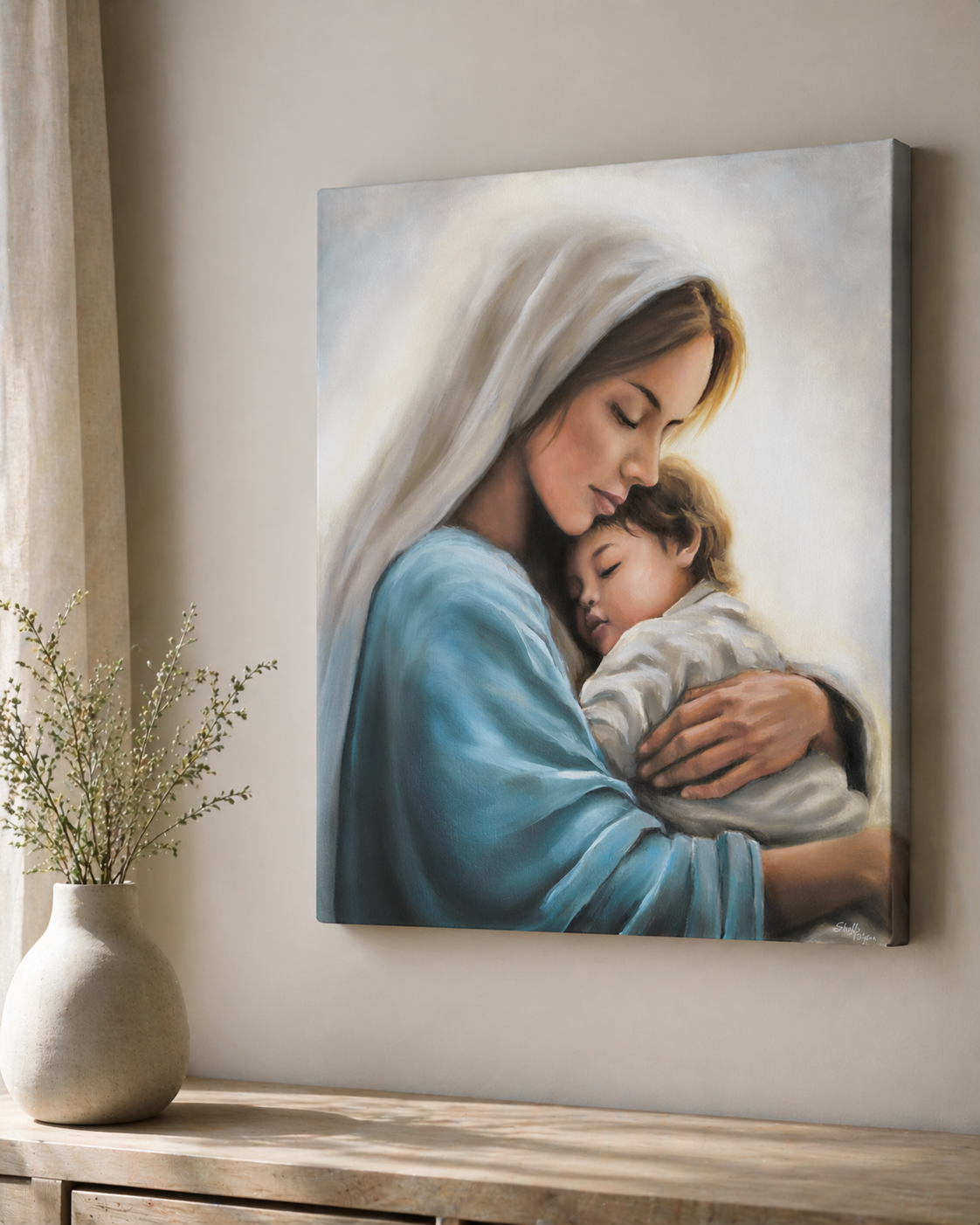 Canvas print of Mary holding little Christ. Canvas on a wall above a wooden surface with a vase.
