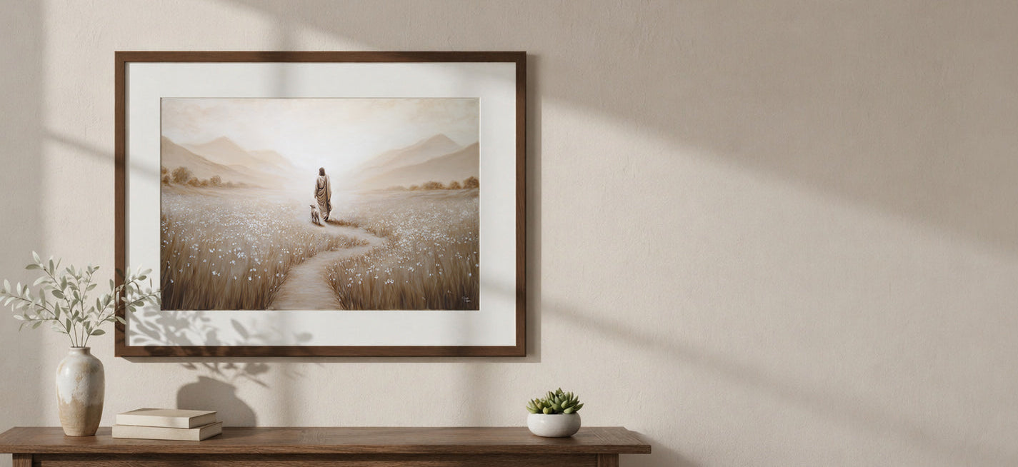 Framed artwork of Christ walking in a field with the lamb on a wall above a wooden console table.